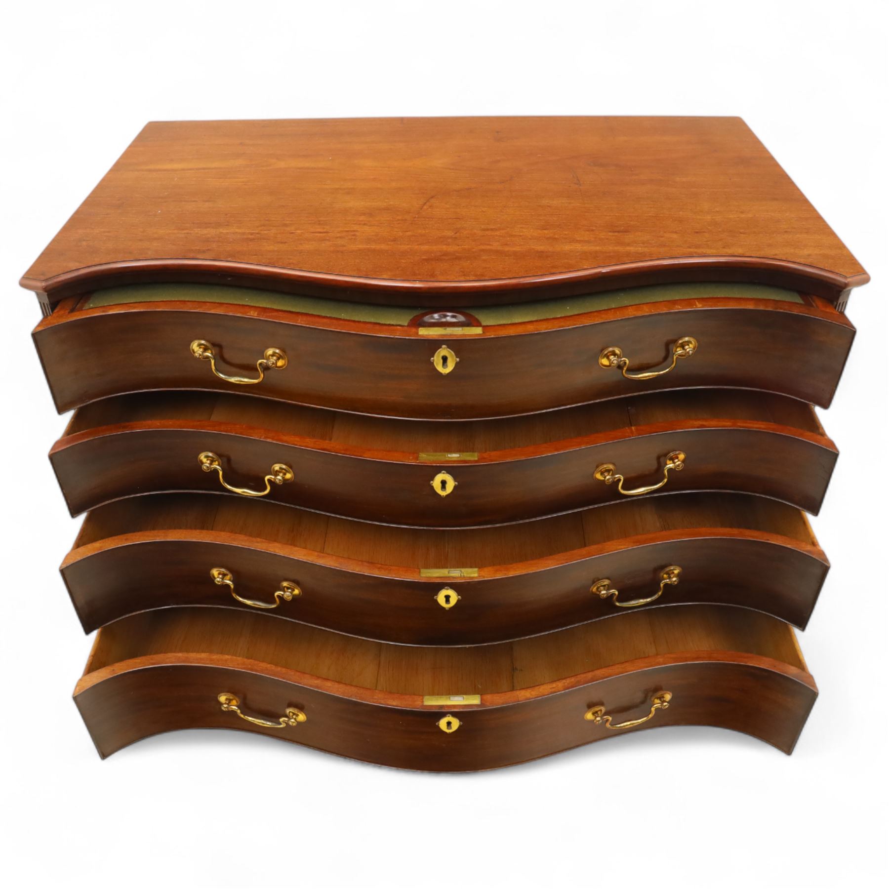 George III mahogany serpentine chest, moulded top over four cock-beaded drawers, the top drawer fitted with baize lined slide opening to reveal divisions,  enclosed by canted and fluted upright corners, the drawer fronts fitted with brass swan neck handles and circular plates with oval escutcheons, lower moulded edge over bracket feet, on lignum vitae castors
