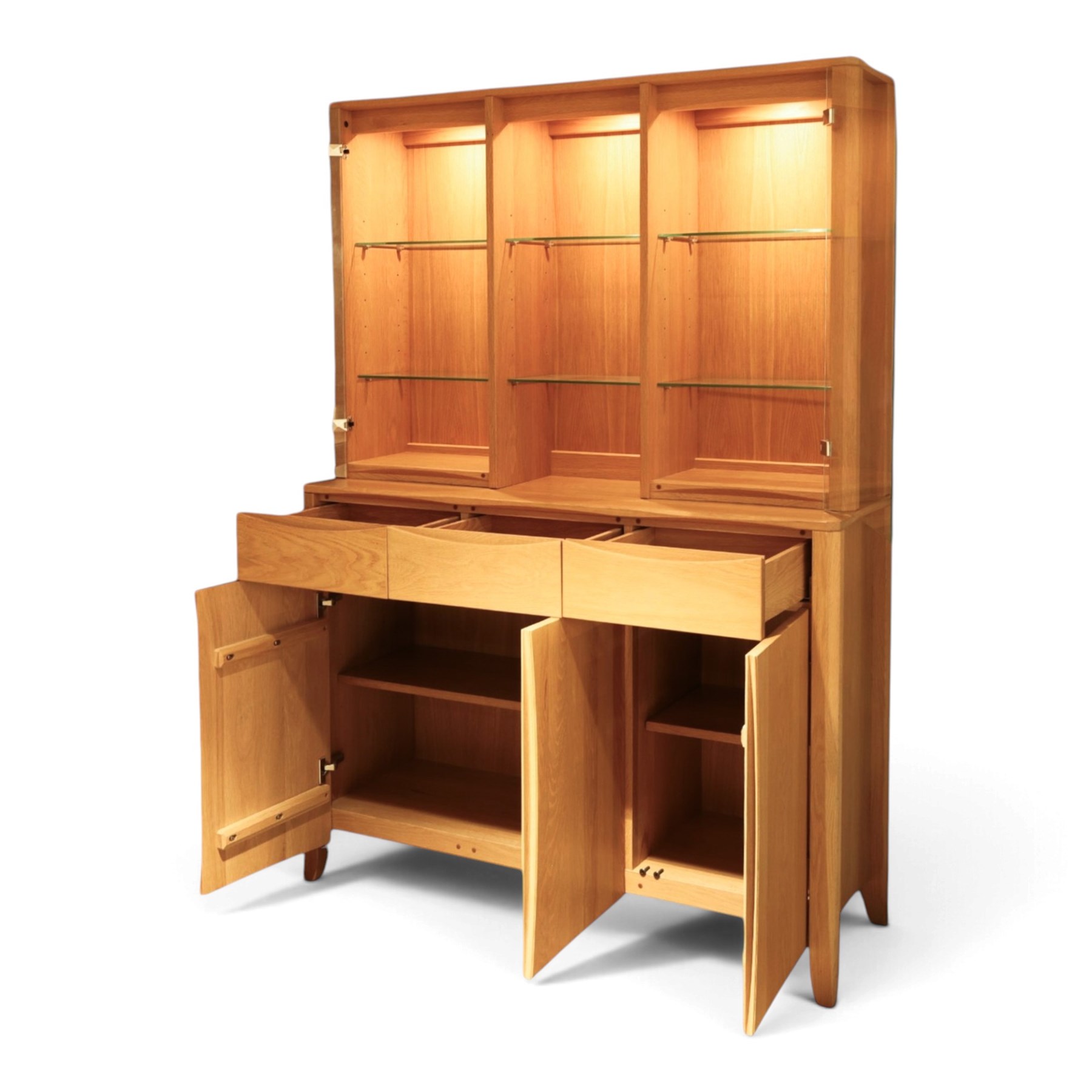 Ercol - 'Artisan' light oak dresser, upper section with cantered corners, with central open area fitted with adjustable glass shelves, flanked by twin glazed cabinets with further adjustable glass shelving, the lower section with three shorts drawers with recessed handles, above three cupboard doors with recessed handles enclosing adjustable wooden shelves, raised on short tapering supports 