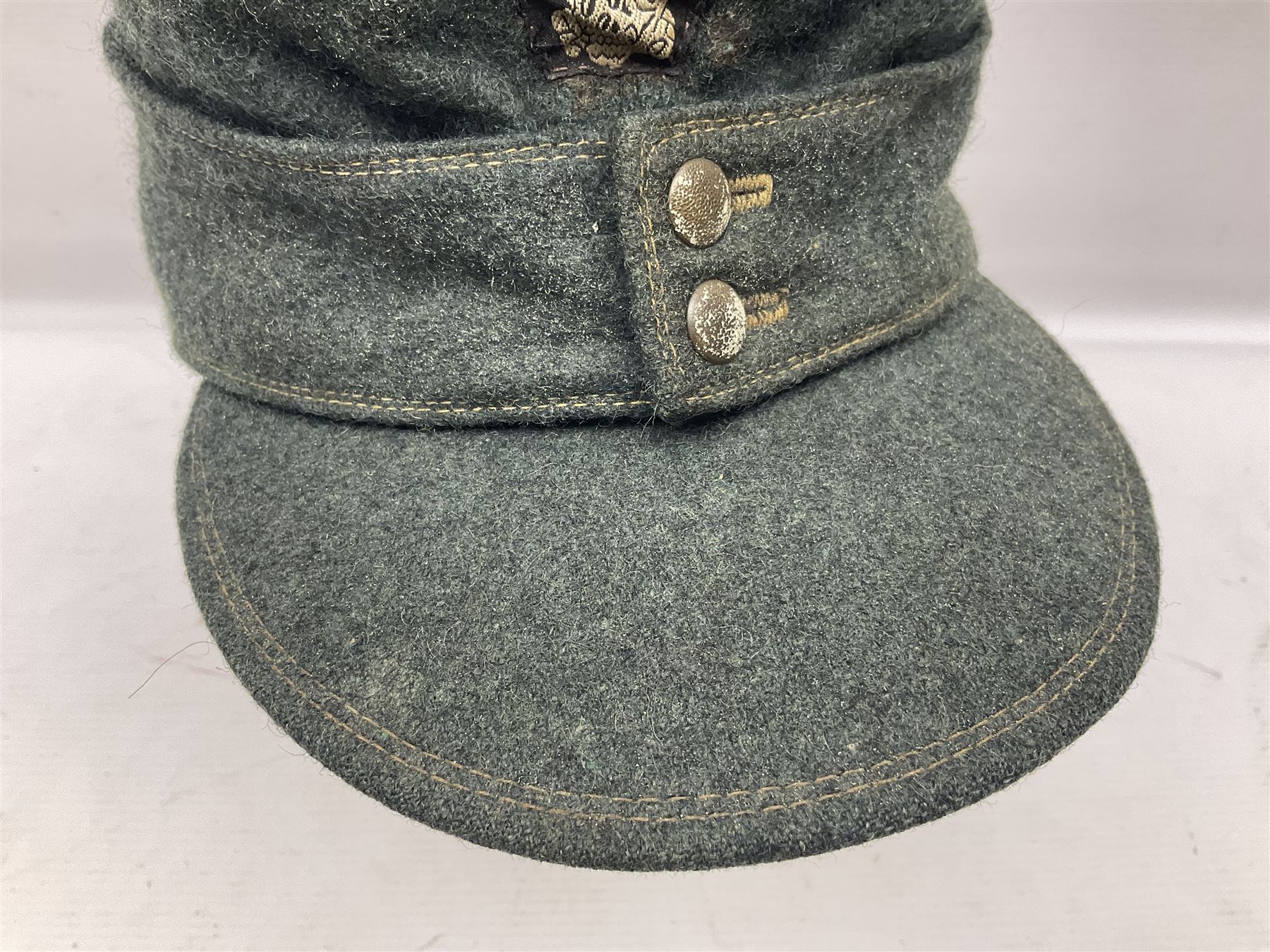 WWII German M43 field cap with 'SS' cloth badge and mountain trooper's edelweiss metal badge