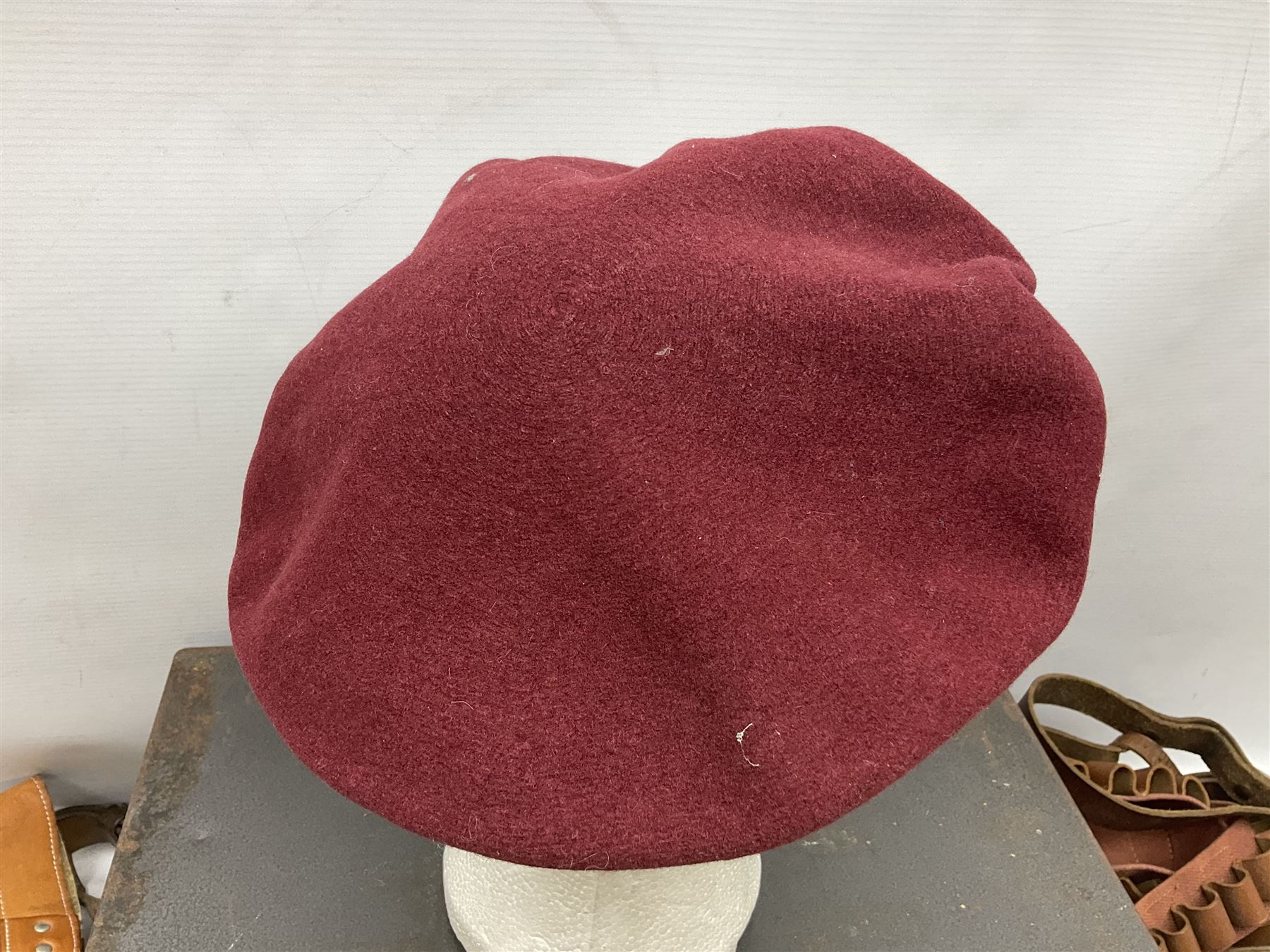 Assorted militaria including ten leather or canvas cartridge and other belts, maroon beret with 17th Lancers cap badge, modern bullet mould, leather and brass shot flask, two knives, shell cases, boomerang etc; in tin deed box