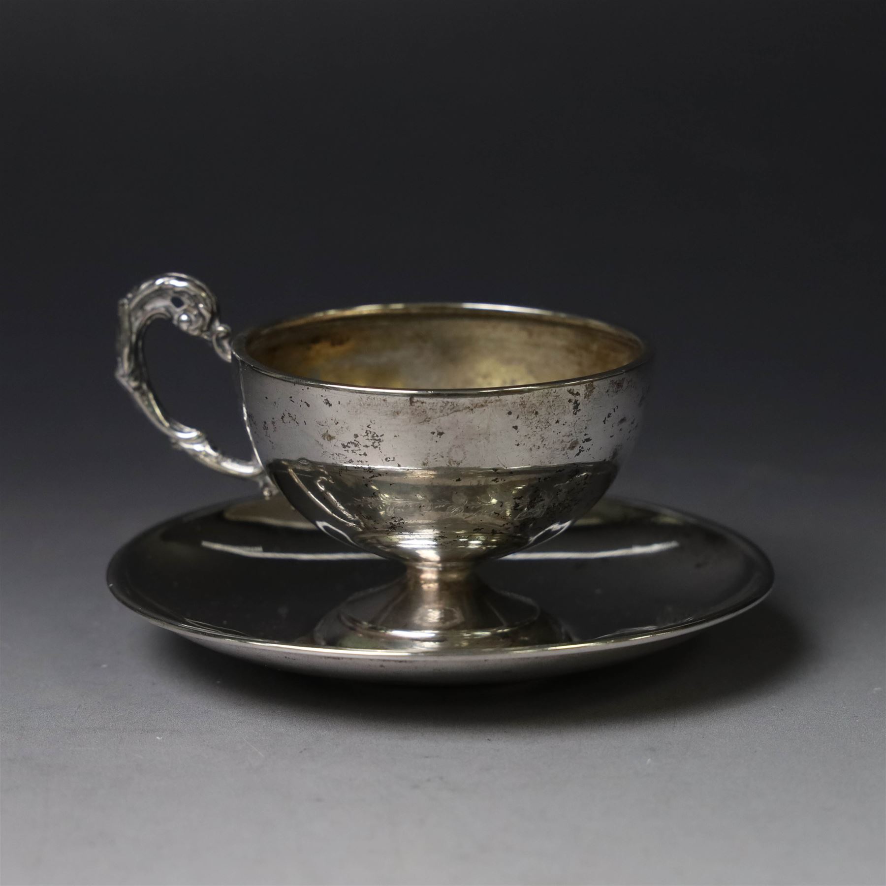 German silver cup and saucer, both with engraved foliate decoration, stamped 800, the saucer with crescent and crown mark