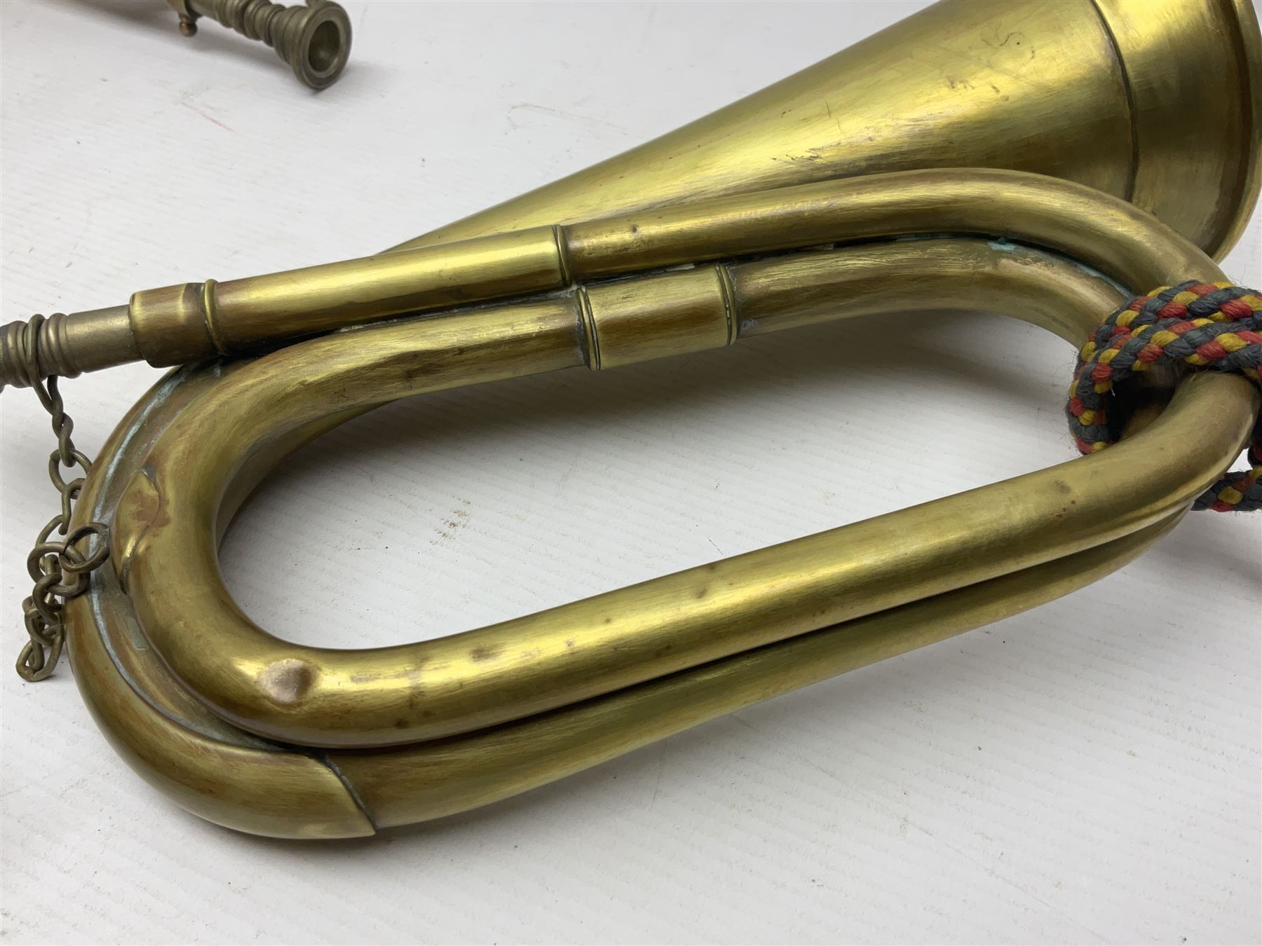 Two military brass bugles by Mayers and Harrison Ltd. Manchester each with crows foot mark and dated 1966; both with multi-coloured cord and tassels, longest 52.5cm (2)