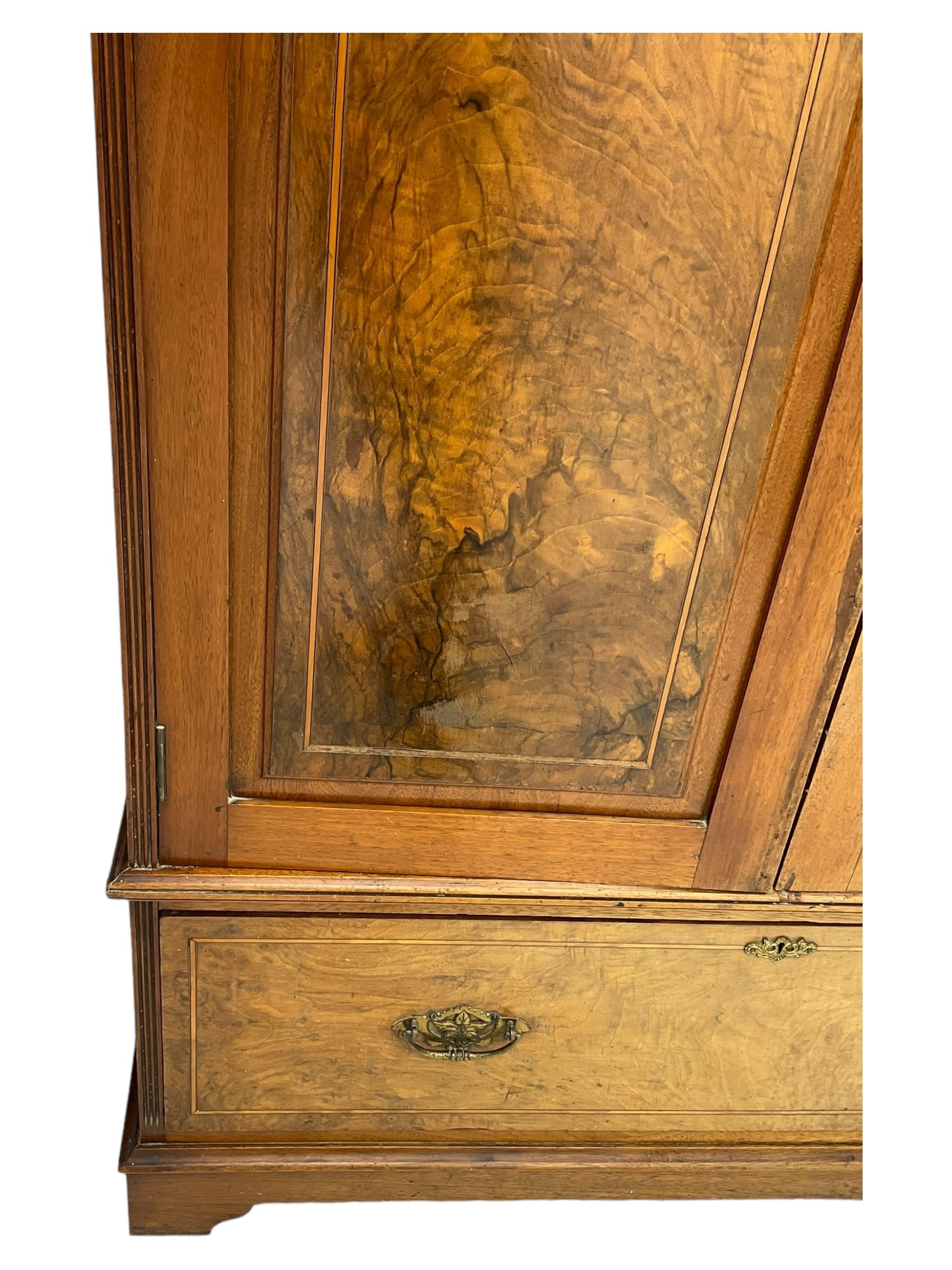 Late Victorian walnut triple combination wardrobe, projecting moulded and dentil cornice, central shaped bevelled mirror glazed door, cartouche and curled leaf carved panels over figured walnut veneered panels, fitted with drawer to base, on bracket feet