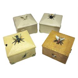 Four square honey boxes with lids,  each decorated with honeycomb pattern and finished with a bee finial