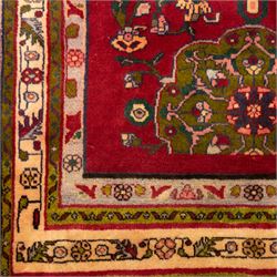 North West Persian Tariz hand-knotted runner, madder red field with a column of linked lozenge medallions in shades of indigo blue and pistachio green framed by stylized floral motifs within triple borders of rosettes and scrolling vines on an ivory ground, with cotton fringe ends