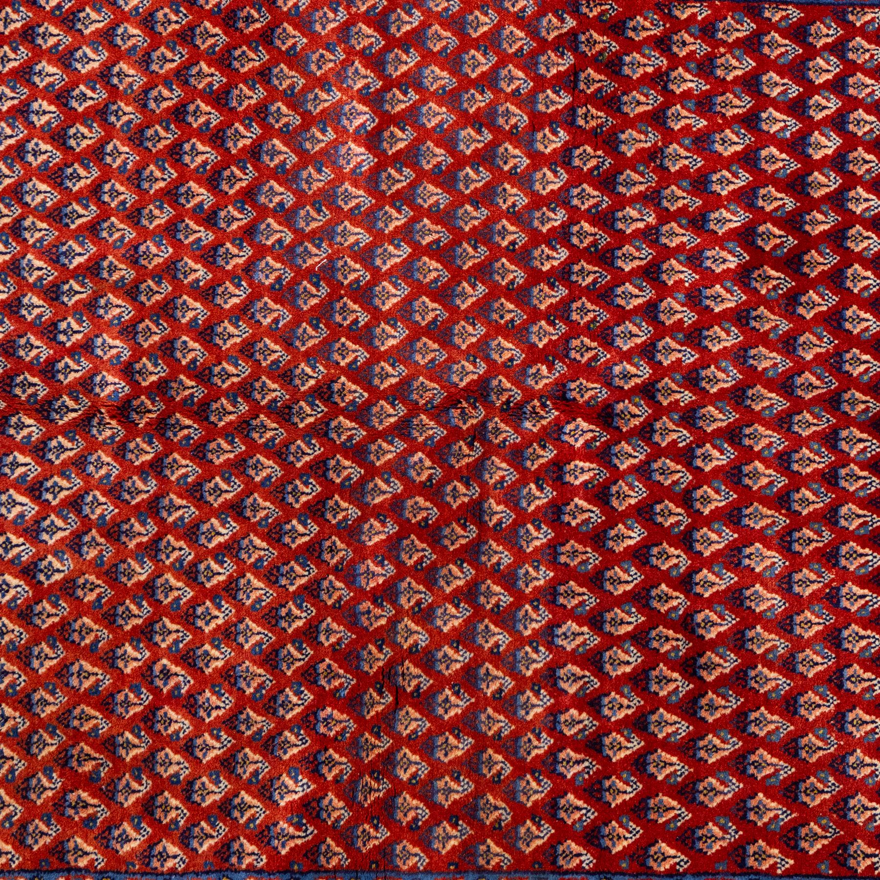 West Persian Saraband (Boteh-Mir) runner madder-red field densely decorated with repeating boteh motifs, arranged in diagonal rows enclosed by a geometric border of stylized motifs, between multiple guard stripes, cotton fringe ends  