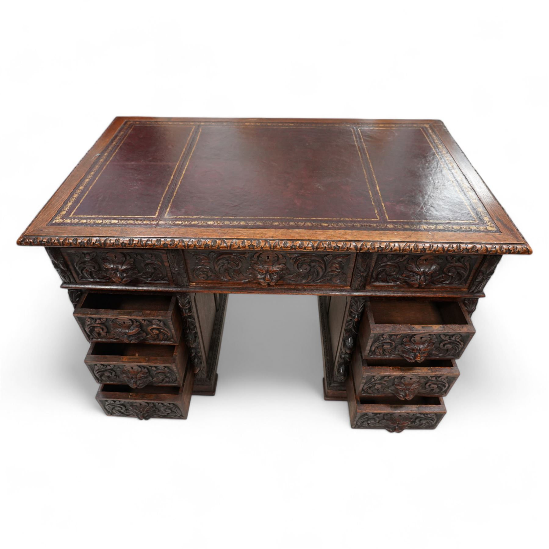 Victorian carved oak twin pedestal desk, moulded and foliate carved rectangular top with leather inset, fitted with nine drawers, each carved with scrolling foliage and lion mask handles, on skirted base 