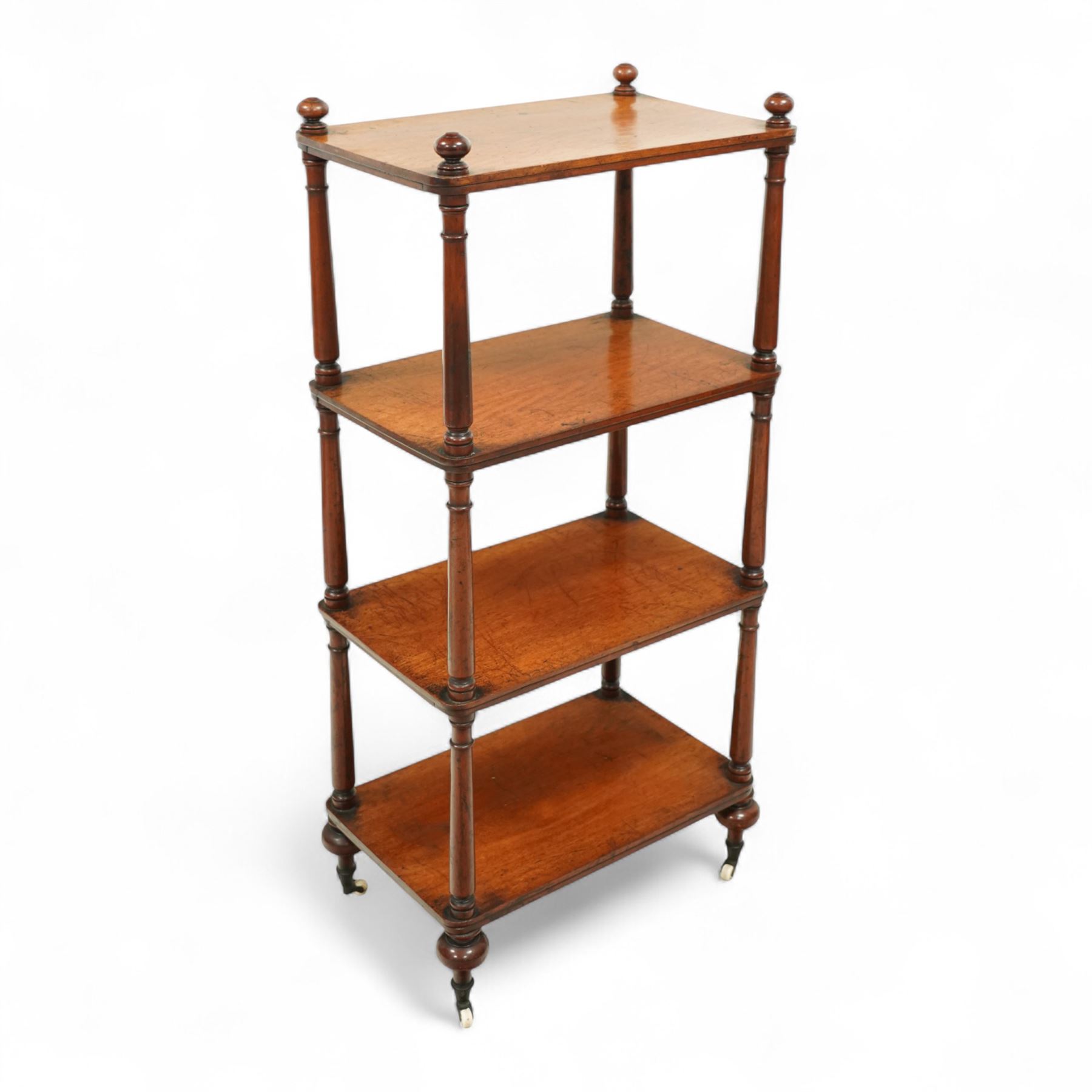 19th century mahogany four-tier whatnot, each rectangular shelf supported by turned uprights with ball finials, raised on turned feet with brass castors