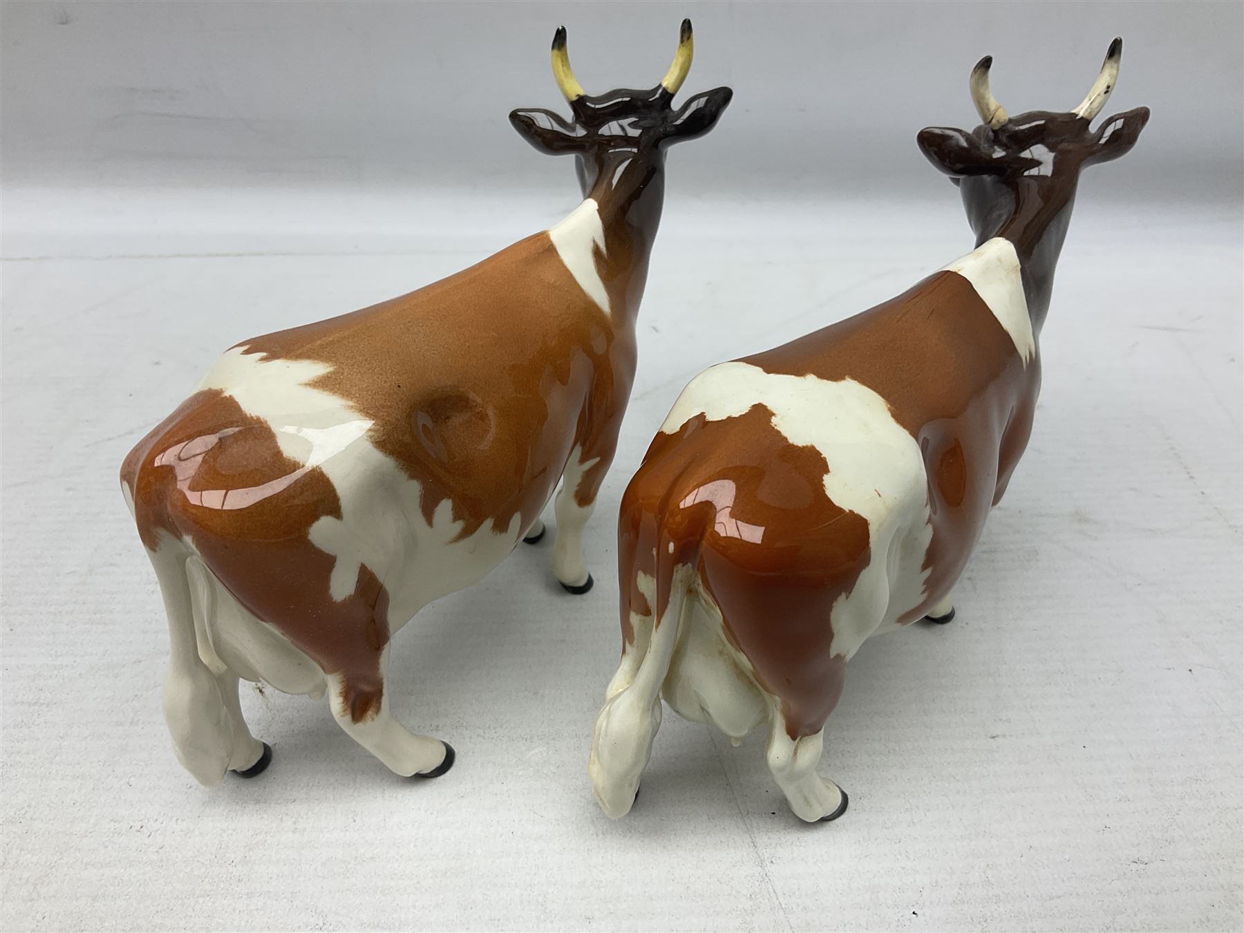 Five Beswick figures of cattle Comprising Ayrshire Bull Ch Whitehill Mandate, no 1454B, three Ayrshire Cow Ch Ickham Bessie, no 1350 and Ayrshire Calf, no 1249B, all with printed marks beneath