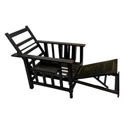 Late Victorian oak steamer chair, adjustable slatted backrest with grooved crest rail, wide armrests extending to a sliding adjustable footrest, open frame sides with vertical slats, side magazine rack and collapsible table, raised on turned front supports