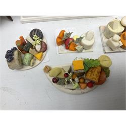 Collection of miniature dolls house grocery shop furniture and produce, comprising glazed corner counter with brass style cash register, shelved preserves unit, pies, cheese board and trays of meats, pair of white cheese counters, biscuit display with six tins, glazed preserves cabinet, pair of shop chairs and four further cheese boards complete with grapes and label flags