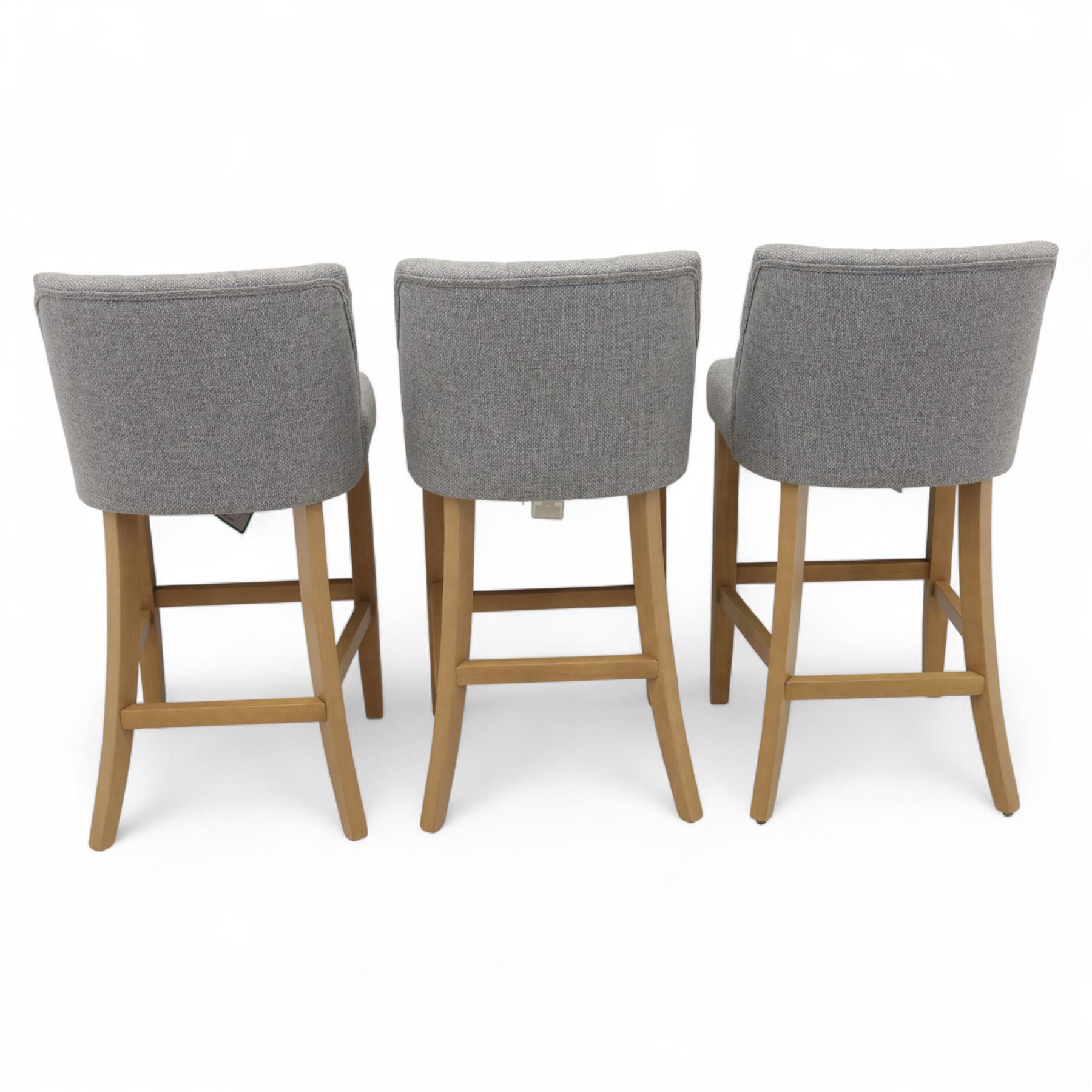 Contemporary set of three upholstered bar stools, each with button-tufted grey fabric backrest and seat, raised on light oak finish square legs united by stretchers