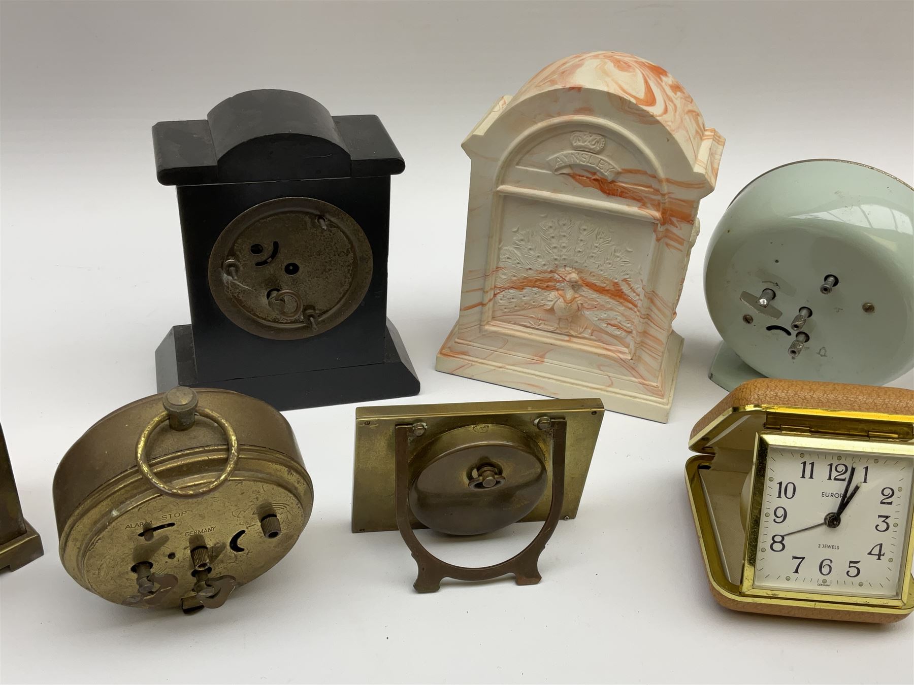 Miniature 'Zenith' travel alarm clock, in engine turned brass case with silvered numerical chapter ring, H5cm, together with other clocks to include Aynsley Portland Ware mantel clock, with moulded peacock design, Europa travelling clock, brass carriage clock, German copper clock of cube form etc