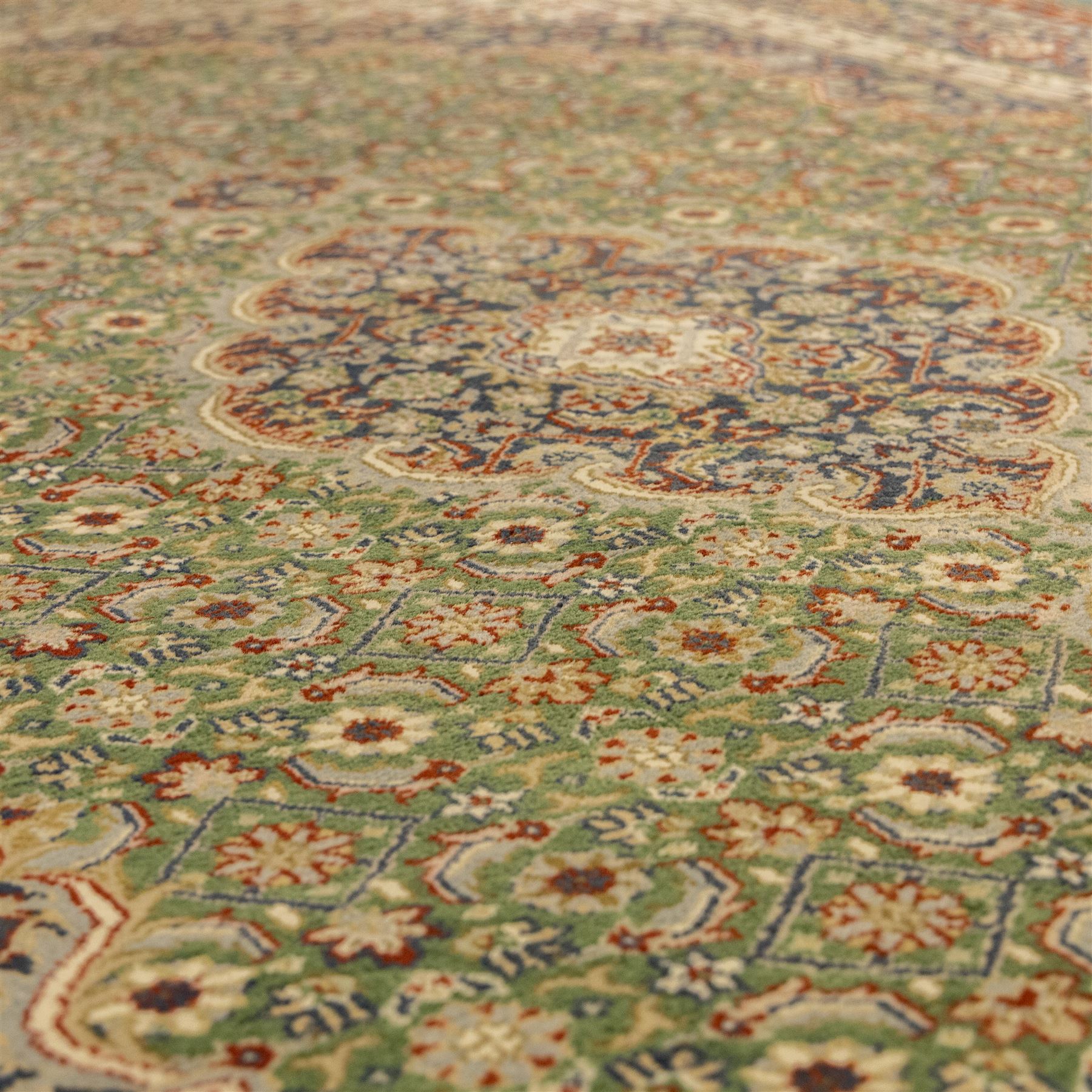 Central Persian Kashan rug, emerald green ground, with a central ivory, indigo, and brick red lobbed medallion with pendant finials, ivory spandrels, framed by multiple floral borders