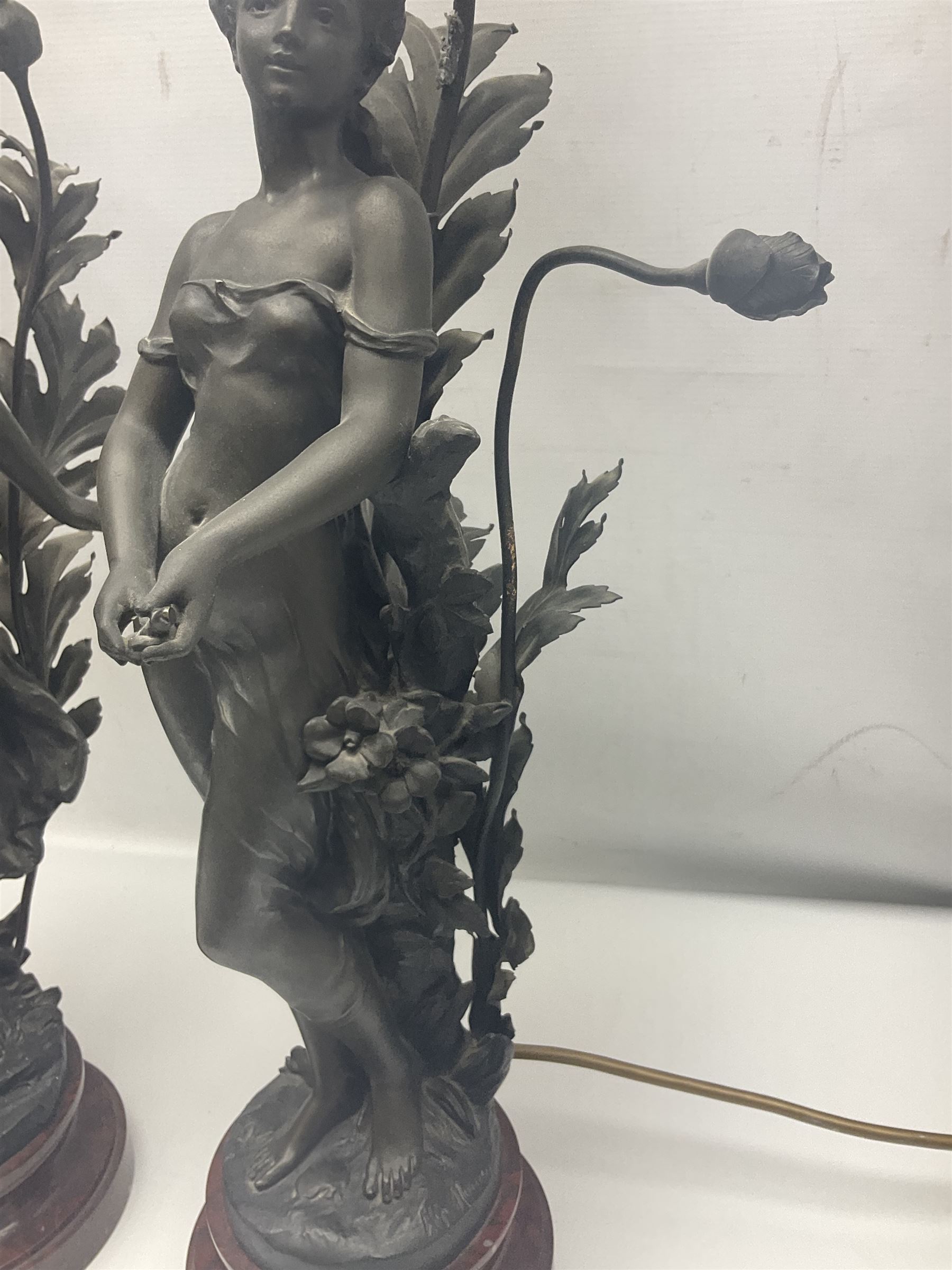 Pair of Art Nouveau style spelter figural table lamps, each mounted on rouge marble effect circular bases, with toleware flower heads and leafy decoration surrounding a female figure, H90cm