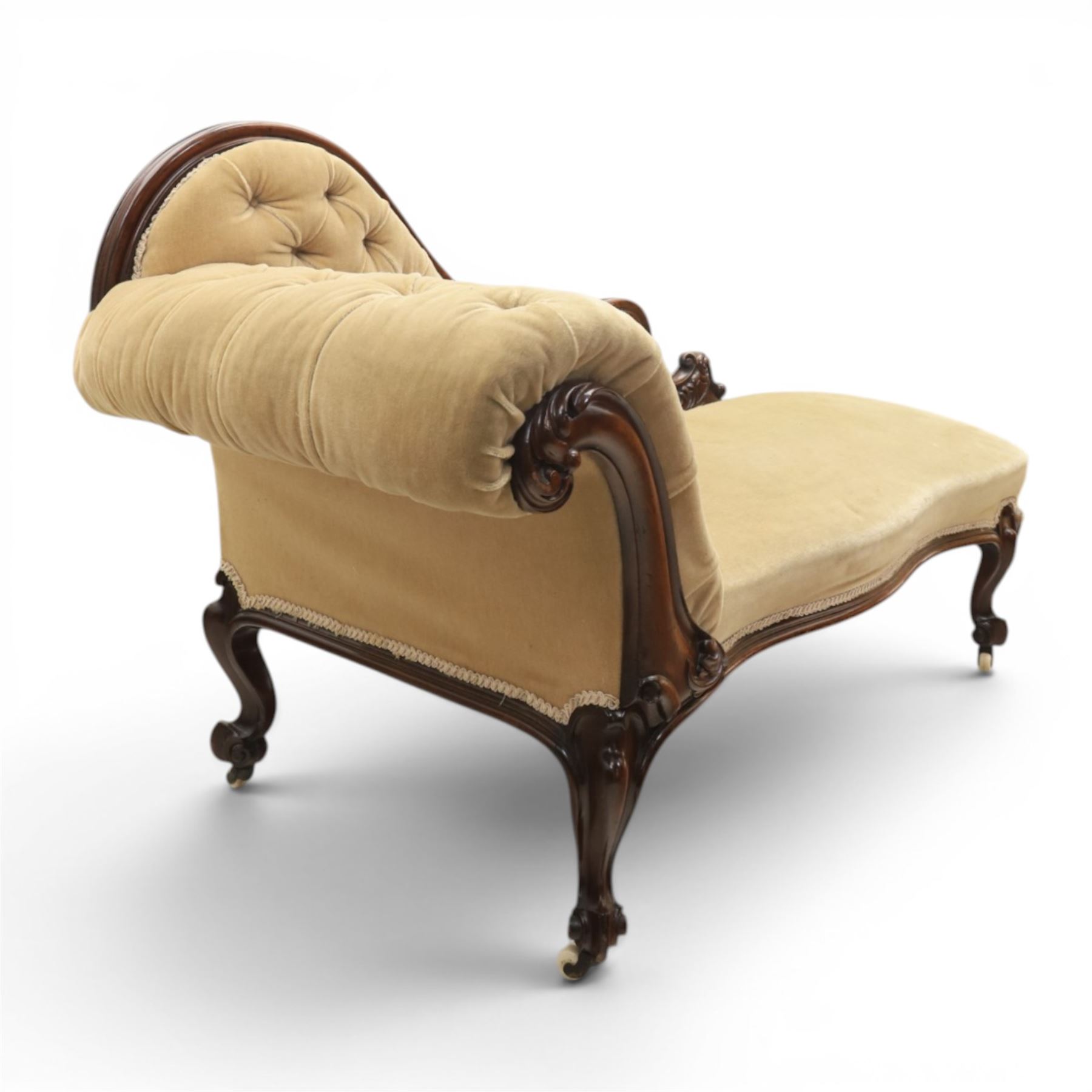 Victorian mahogany chaise lounge, scrolled back rest with deep buttoned back, upholstered in beige velvet, raised on a carved frame raised on cabriole supports terminating in castors 