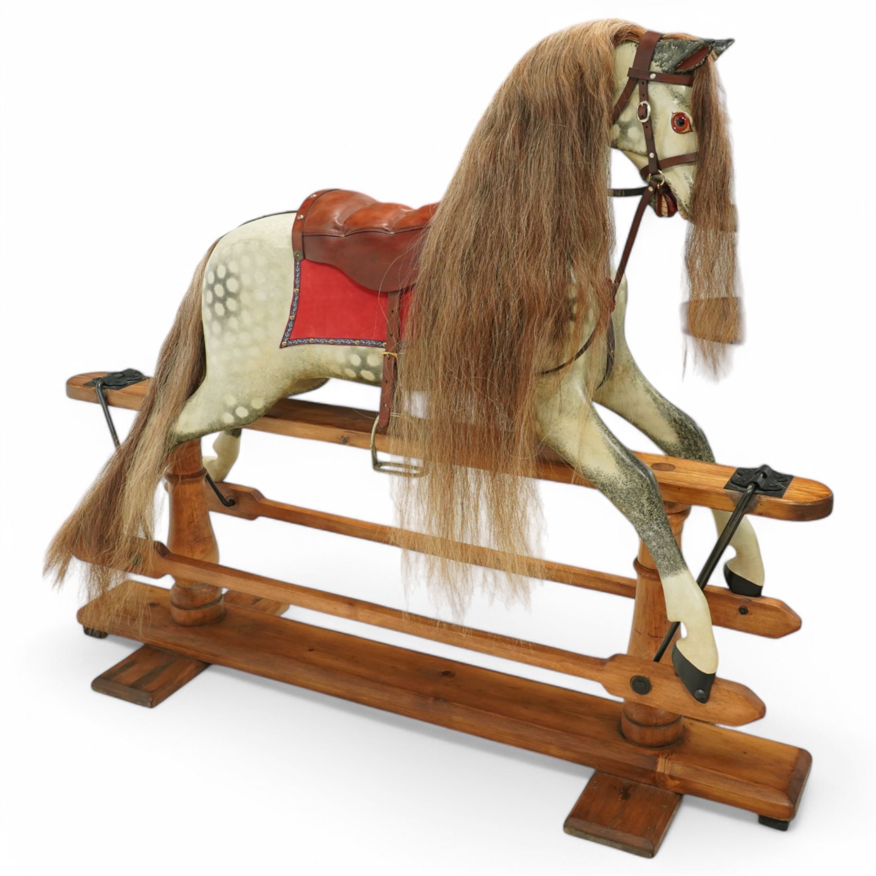Frederick Henry Ayres (F H Ayres, London) - Late Victorian large carved wooden rocking horse, in dapple grey paint finish, decorated with glass eyes, leather reins, stirrup and saddle, indented hooves, on rockers united by chamfered stretchers and boarded base, c.1890