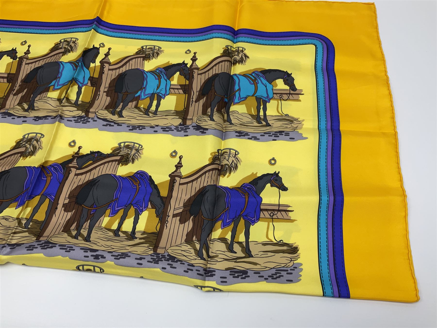 Hermès 'Ecuries' silk scarf, designed by Hugo Grygkar in 1947, printed with twenty horses in their respective stables, on yellow ground contained within stitched effect blue and purple and darker yellow gold borders, with rolled hand stitched edges and Hermes material label, 87cm square