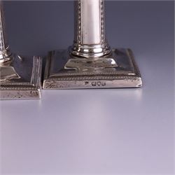 Pair of late Victorian silver mounted candlesticks, the stems embossed with classical ribbon and swag design, upon weighted stepped square bases, hallmarked London 1899, maker's mark worn and indistinct, H12cm