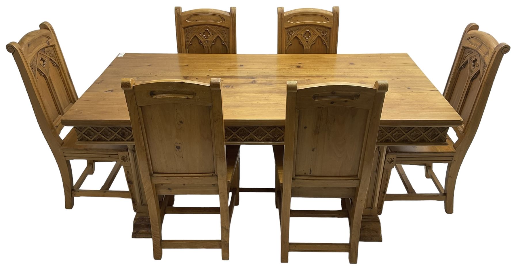 Ecclesiastical Gothic design waxed pine dining table, rectangular top over frieze carved with lattice pattern, raised on square chamfered supports with tracery style carving, on sledge feet joined by stretcher (W185cm D90cm H77cm); and set six matching chairs, high panelled back with carved and moulded gothic tracery window decoration and flower heads, panel seat over carved frieze rail and square tapering supports (W48cm H104cm)