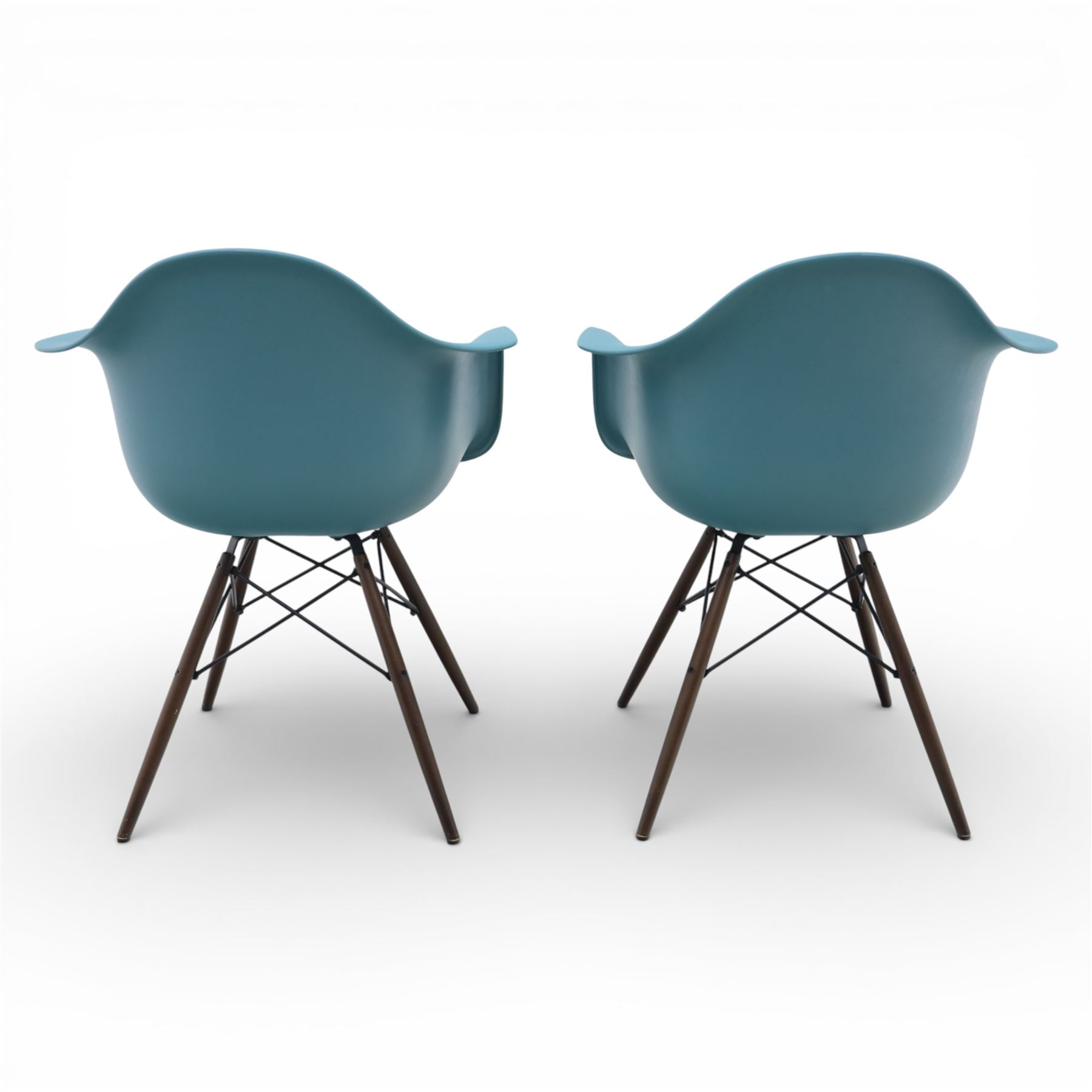 Vitra - Pair of Eames DAW armchairs, moulded plastic seats in teal with integrated armrests, blue upholstered seat cushions, supported on stained wooden dowel legs with black wire cross bracing