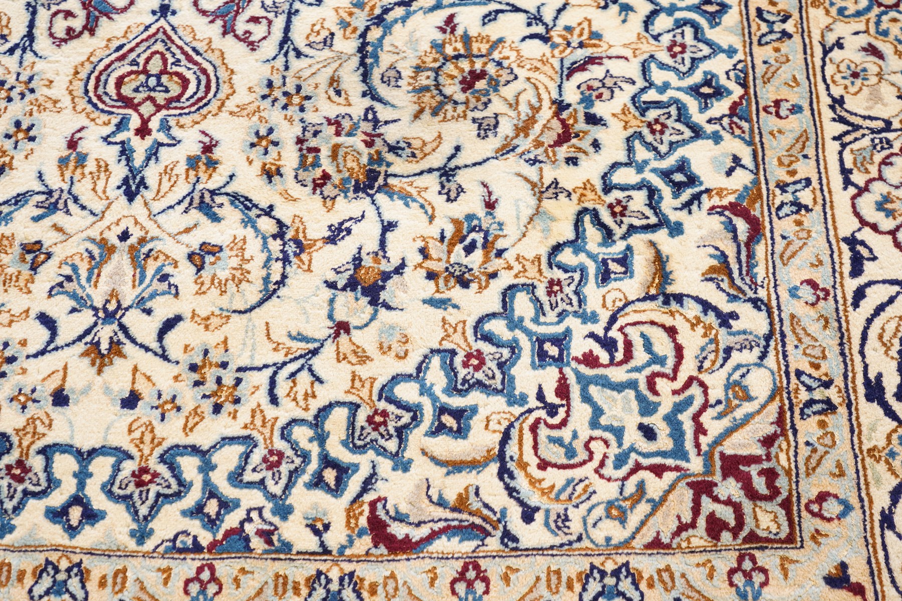 Persian Nain ivory ground rug, the busy oval field profusely decorated with scrolling foliate decoration and palmettes in citrine and indigo tones, the central medallion with matching spandrels, the multiple guard bands with repeating stylised quatrefoil motifs and trailing scrolling foliage and flowerheads