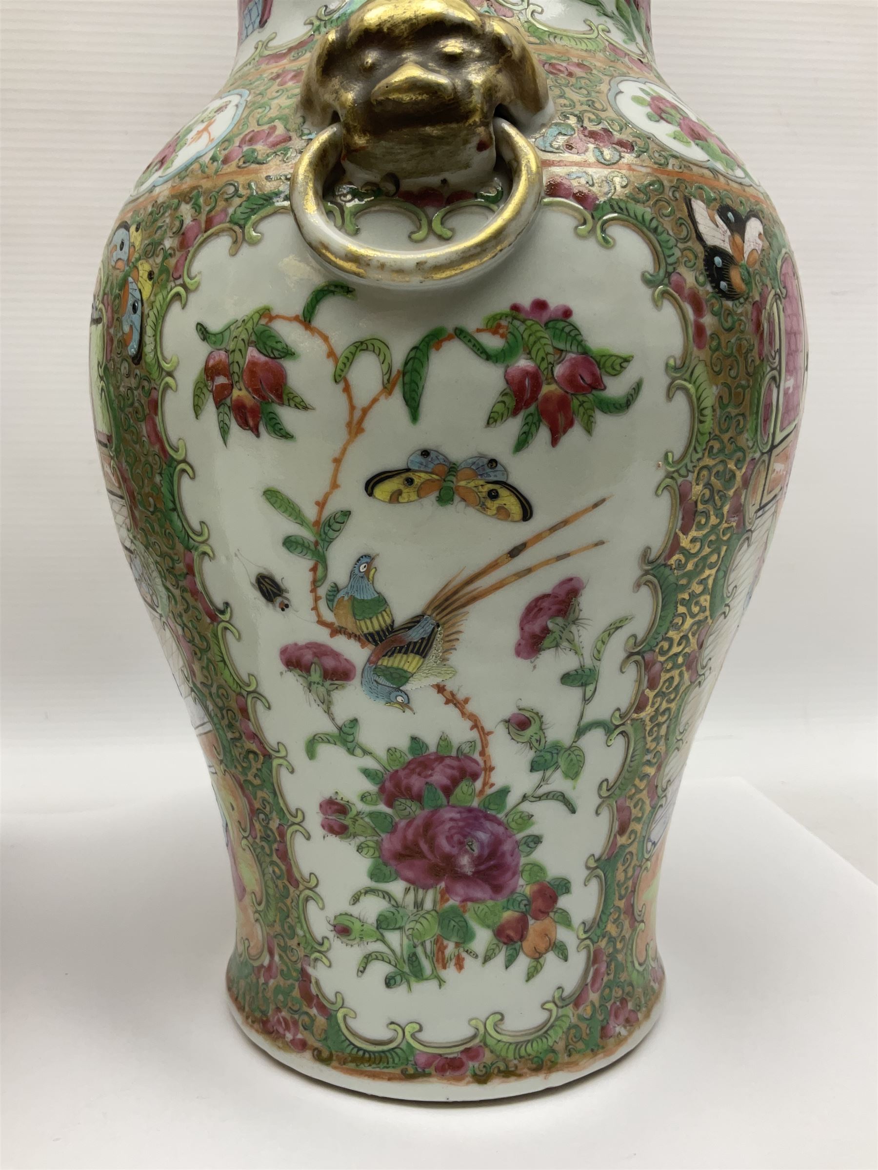 Pair of 19th century Chinese Famille Rose vases and covers, each of baluster form with twin gilt lion mask ring handles to shoulders, the flattened domed covers with gilt temple lion finials, each decorated with alternating reserves of bijin and attendants, and birds and butterflies amongst blossoming peonies, against a gilt ground profusely decorated with stylised scrolls, H32.5cm