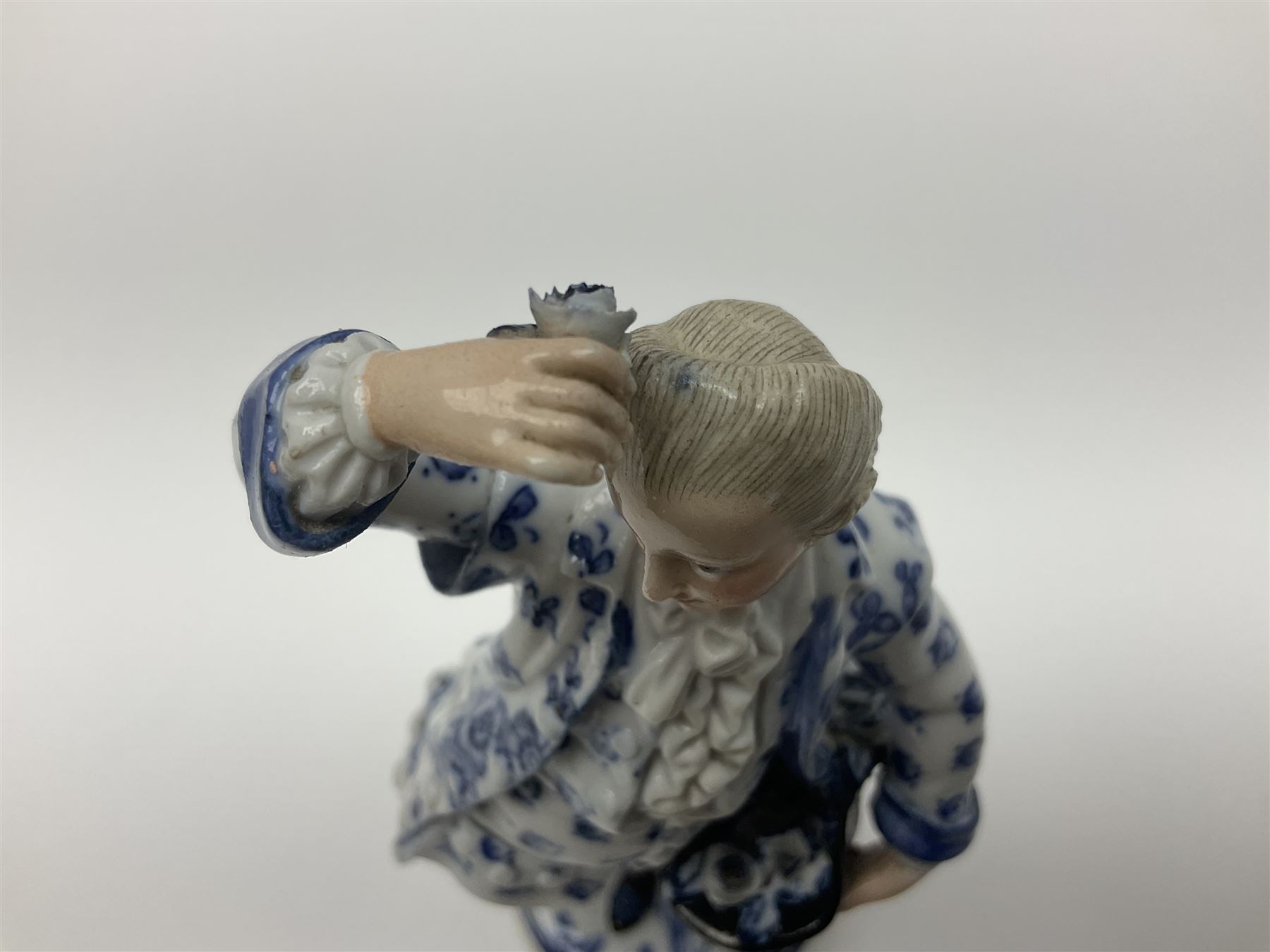 Meissen blue and white figure, modelled as a gentleman holding a hat of flowers, raised upon Greek key design base, with blue crossed swords and impressed C 73 and 149 marks beneath, H18cm