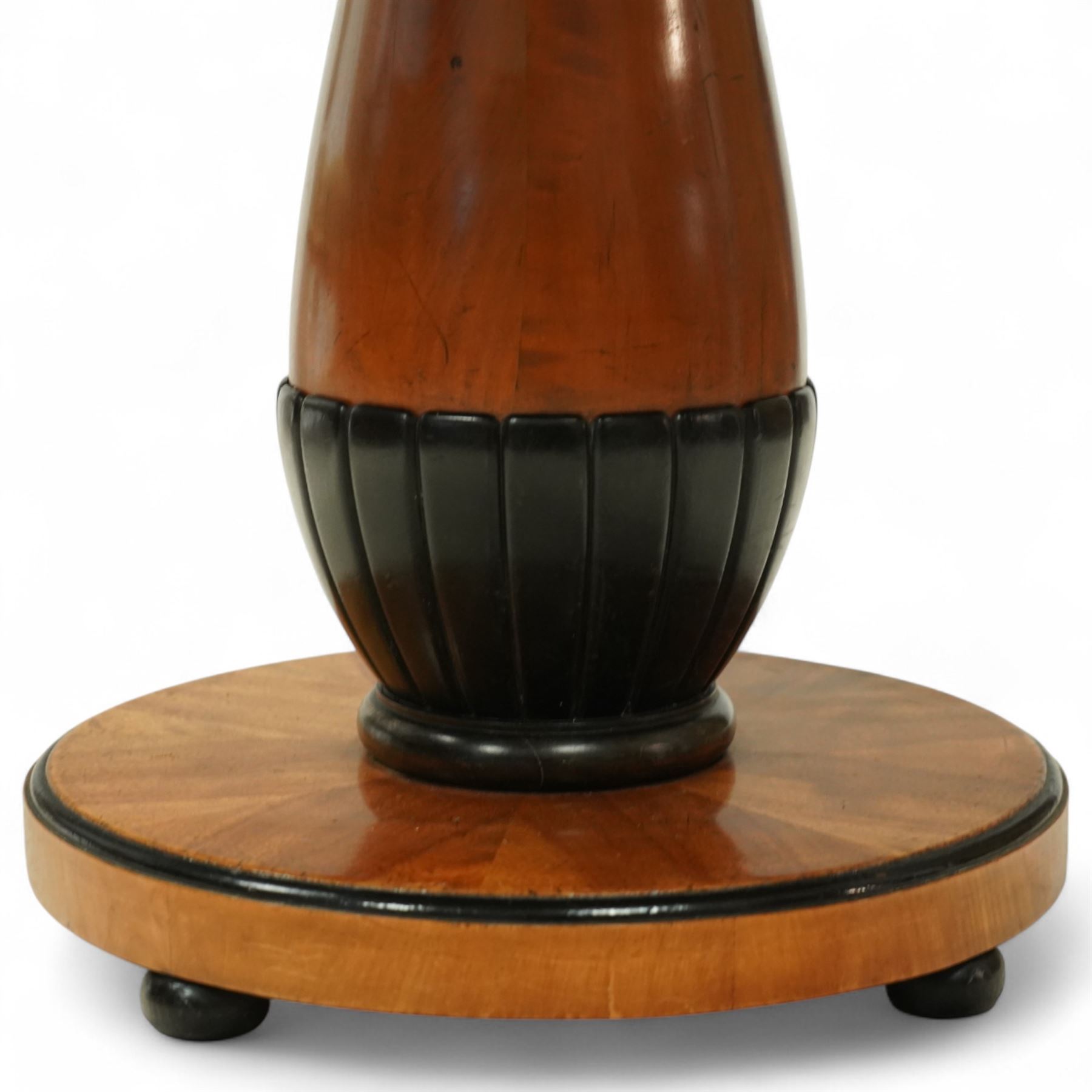 Mid-20th-century Biedermeier-style ebonized and satinwood pedestal table, quarter-veneered circular top with ebonized edge above a tapered baluster quarter-lobed column, raised on a circular plinth base, D87xH70cm, together with two matching upholstered spoon back chairs W45xD47xH87cm