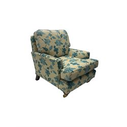 Traditional shaped armchair, upholstered in blue and cream floral fabric, on tapered supports with castors 
