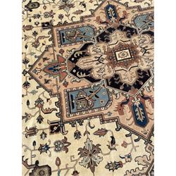 Persian Heriz pale olive and ivory ground carpet, large quatrefoil medallion with palmettes, the surrounding field decorated with trailing leafy branches and stylised plant motifs, peach ground borders with overall floral pattern, within guard stripes 