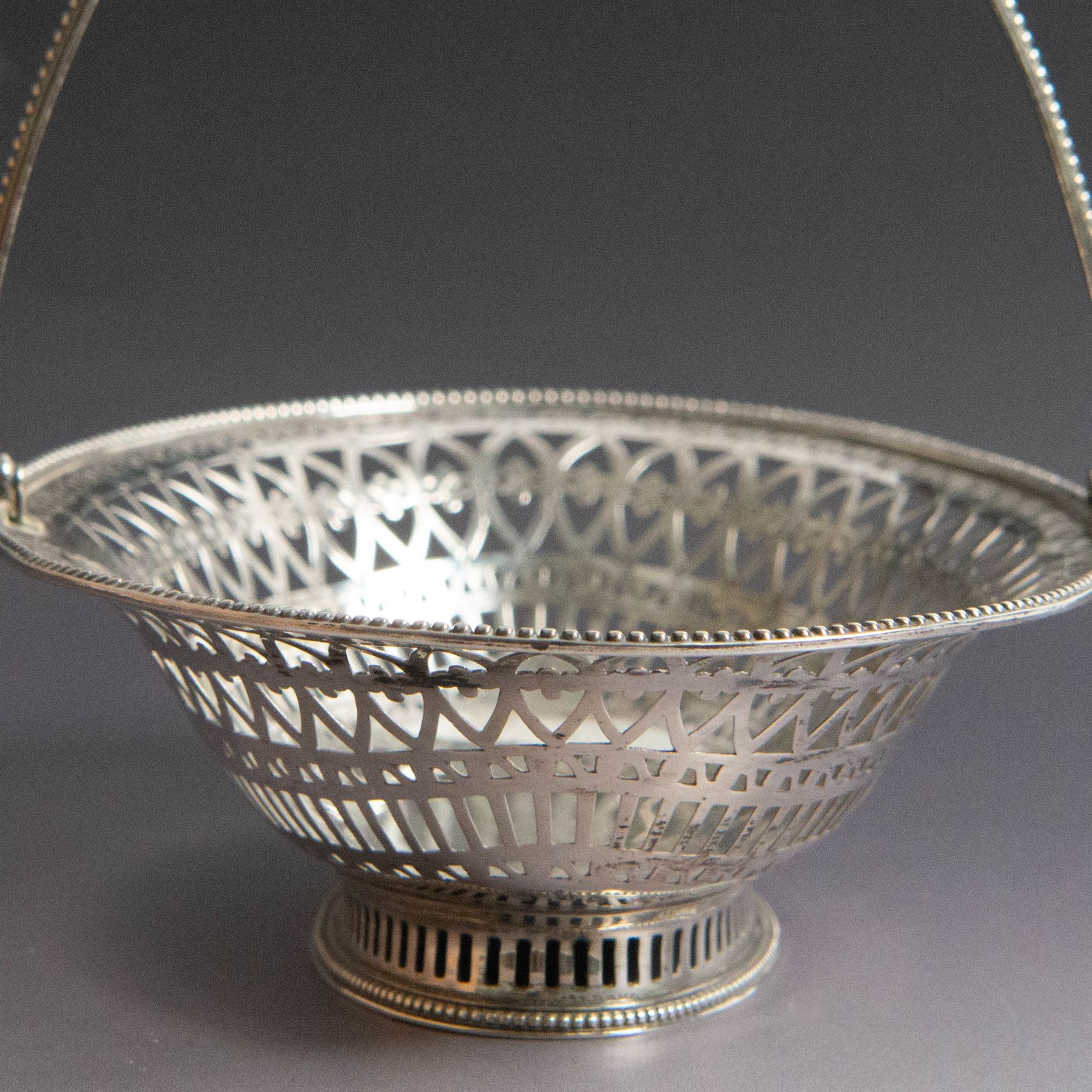 George III silver bon bon basket, of oval form with bead rim and swing handle, the sides with pierced latticework decoration, hallmarked Hester Bateman, London 1785, handle H14cm