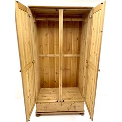 Solid pine double wardrobe, two doors enclosing hanging rail above single drawer, turned supports 