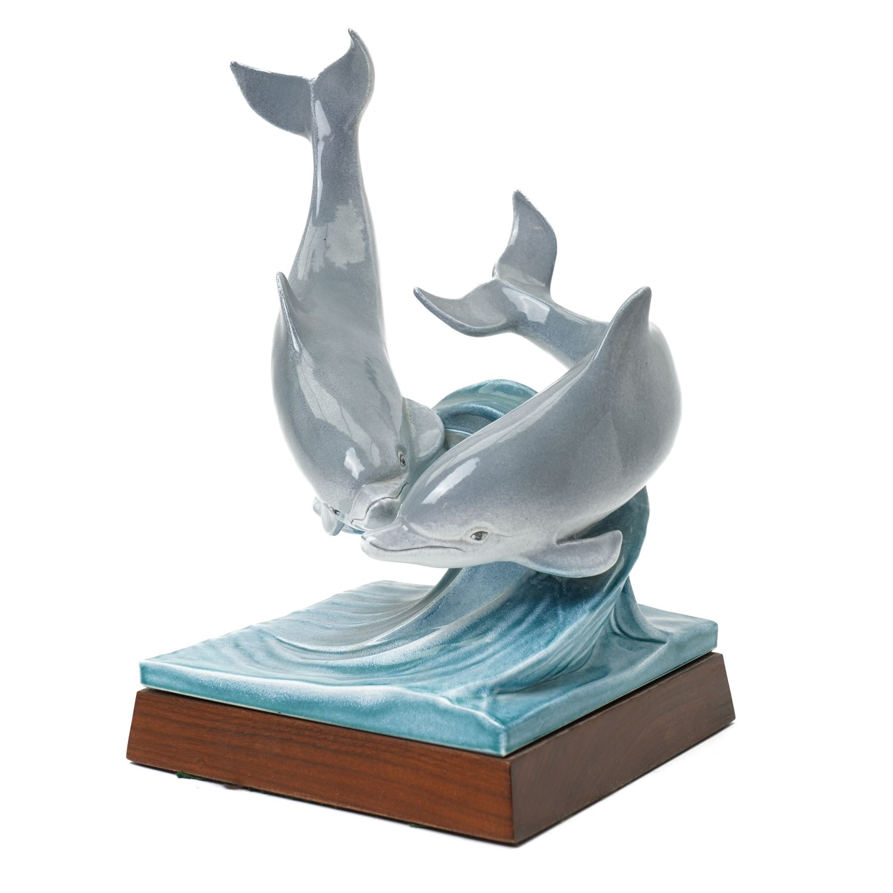 Tony Morris for Poole Pottery, leaping dolphin group, modelled over waves and mounted on a wooden base, H29cm. This model is a duplicate of a sculpture presented to Queen Elizabeth II and the Duke of Edinburgh on their visit to Poole Pottery in 1979, the original cast was destroyed after the production of the duplicate. Provenance: Arnold Smith, Chairman of Pool Potteries Collection