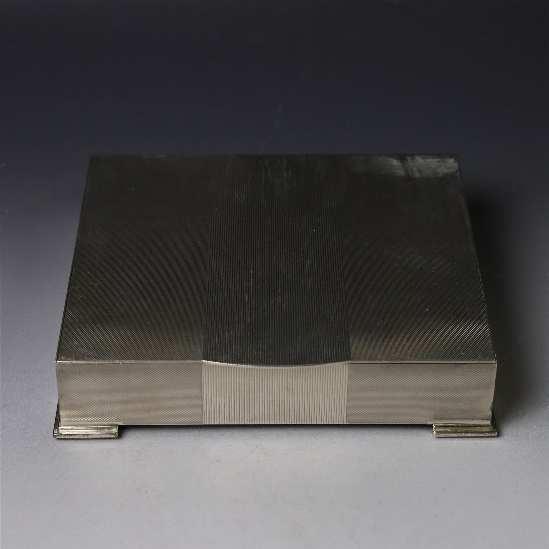 1960s silver mounted cigarette box, of rectangular form with engine turned decoration, upon four bracket feet, with presentation engraving to interior lid reading  'British Aircraft Corporation (Operating) Limited Commemorating the Queen's Award to Industry 1967, hallmarked James Geraghty, Birmingham 1965, with retailers mark for Asprey, W16.5cm, H4.5cm