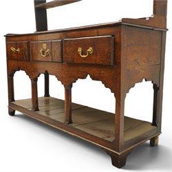 18th century Georgian oak dresser base with plate rack, the three-tier plate rack with shaped frieze, the base with rectangular top with raised back fitted with five spice drawers, over three drawers with brass swan neck handles, raised on six square chamfered supports united by undertier 