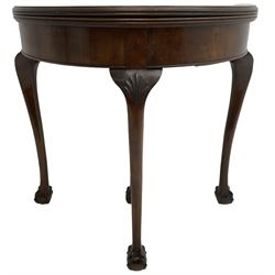 Early 20th century figured walnut demi-lune card table, fold-over reed moulded top with baize lined interior, pull-out rear support with storage well, on shell carved cabriole supports with ball and claw feet