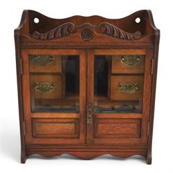 19th century oak table top smokers cabinet, with carved foliate pediment, the two beveled ...