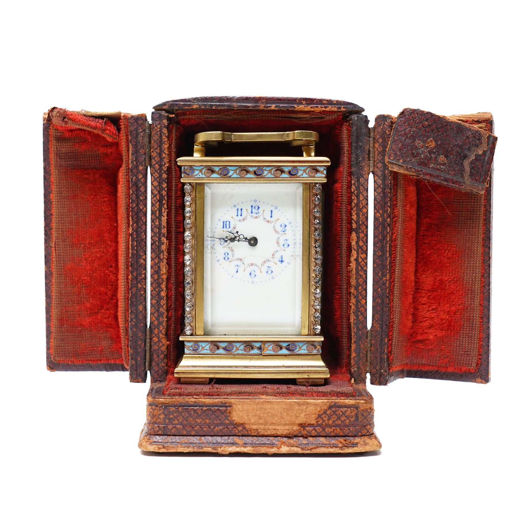 French- Edwardian miniature brass 8-day timepiece carriage clock with cloisonné panels to both base and cornice and paste gems to the front columns, decorative porcelain dial with a floral swag, blue Arabic numerals, minute track and pieced steel hands, square viewing glass to the top with a silvered lever escapement, with original leather bound traveling case.