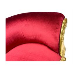Victorian design giltwood chaise longue, the curved backrest and seat upholstered in deep red velvet with tufted detailing, the frame carved with floral motifs and scrolling acanthus leaves, raised on shaped cabriole supports