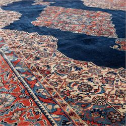 Large West Persian Bidjar hand-knotted carpet, deep indigo field with central medallion with pendants issuing an all-over design of scrolling vines, palmettes, and floral sprays, within conforming spandrels, enclosed a broad madder red palmette, and vine border framed by guard stripes, in a palette, of indigo, madder red and ivory tones, with cotton fringe ends 