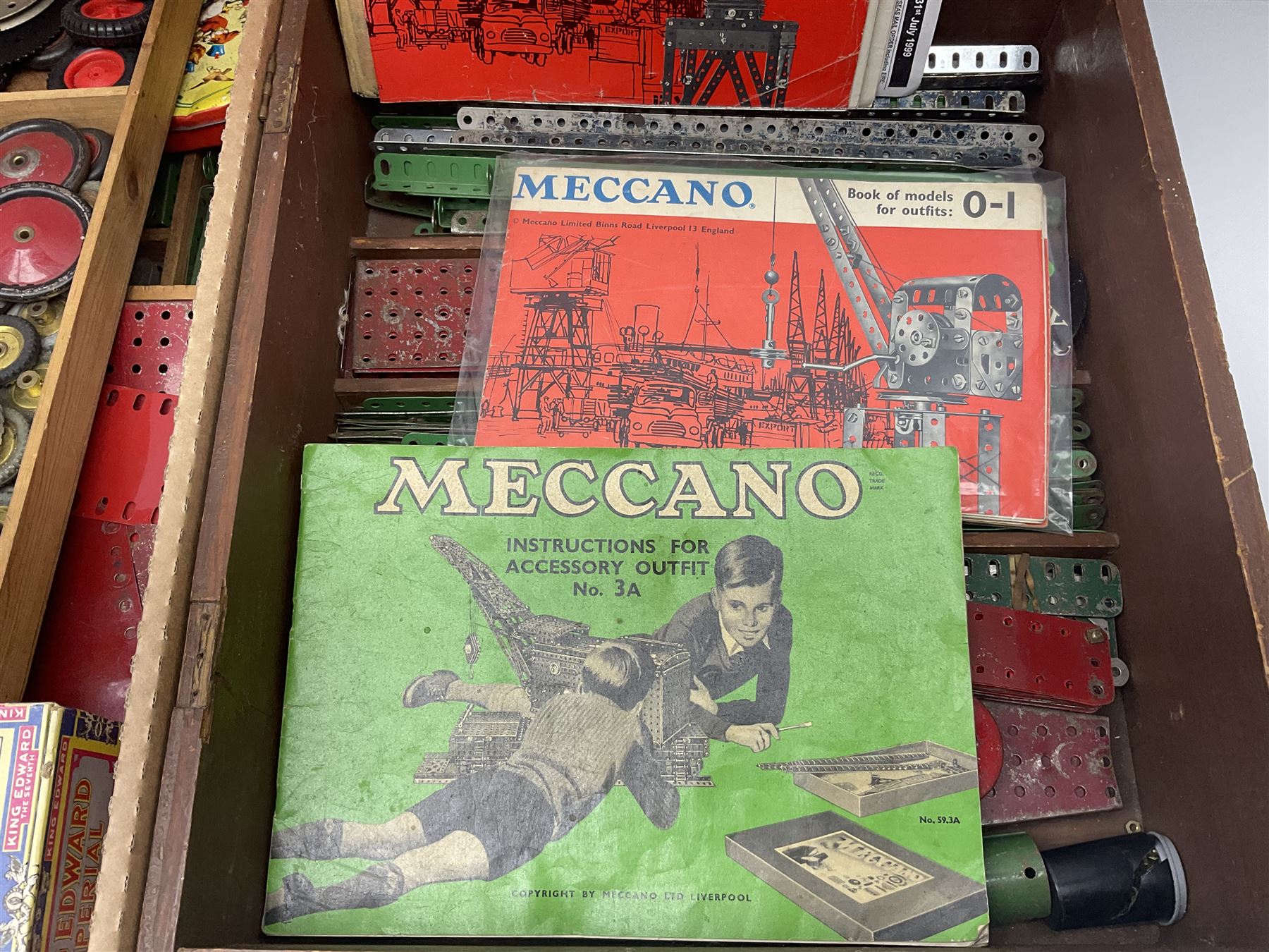 Meccano - large quantity of loose parts including various plates and strips, flanged plates, pulleys, axle rods and crank handles, wheels and tyres, gear wheels, brackets, nuts & bolts, various manuals; predominantly red and green; some in compartmentalised wooden trays