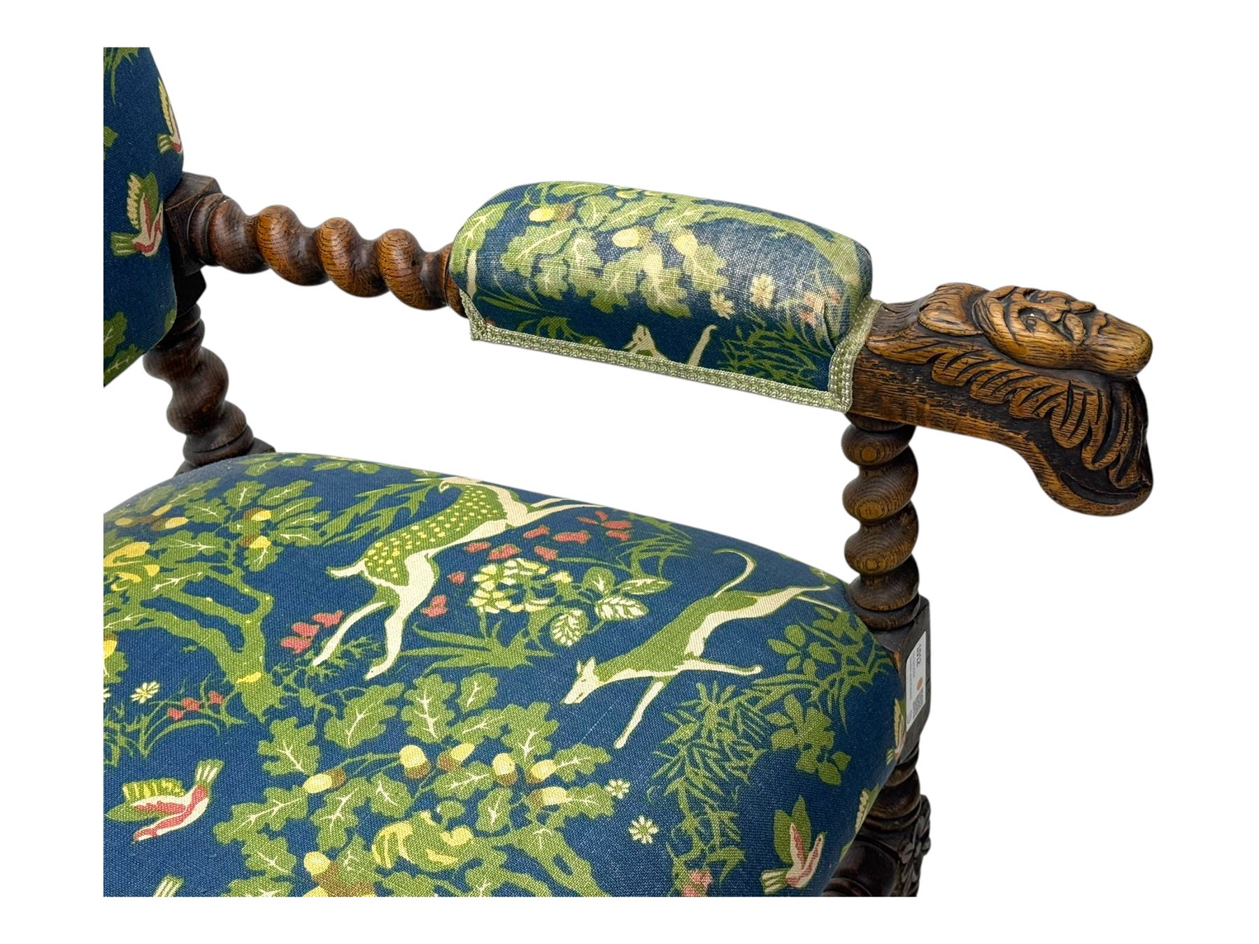 19th century Carolean design oak armchair, upholstered in a vibrant fabric depicting woodland and wildlife scenes, carved lion mask arm terminals, raised on barley twist supports united by H-stretcher