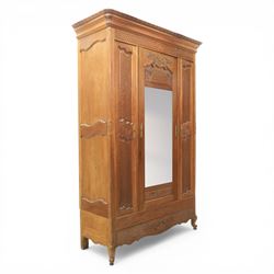 Early 20th century French oak triple door armoire, the moulded top above a frieze with car...