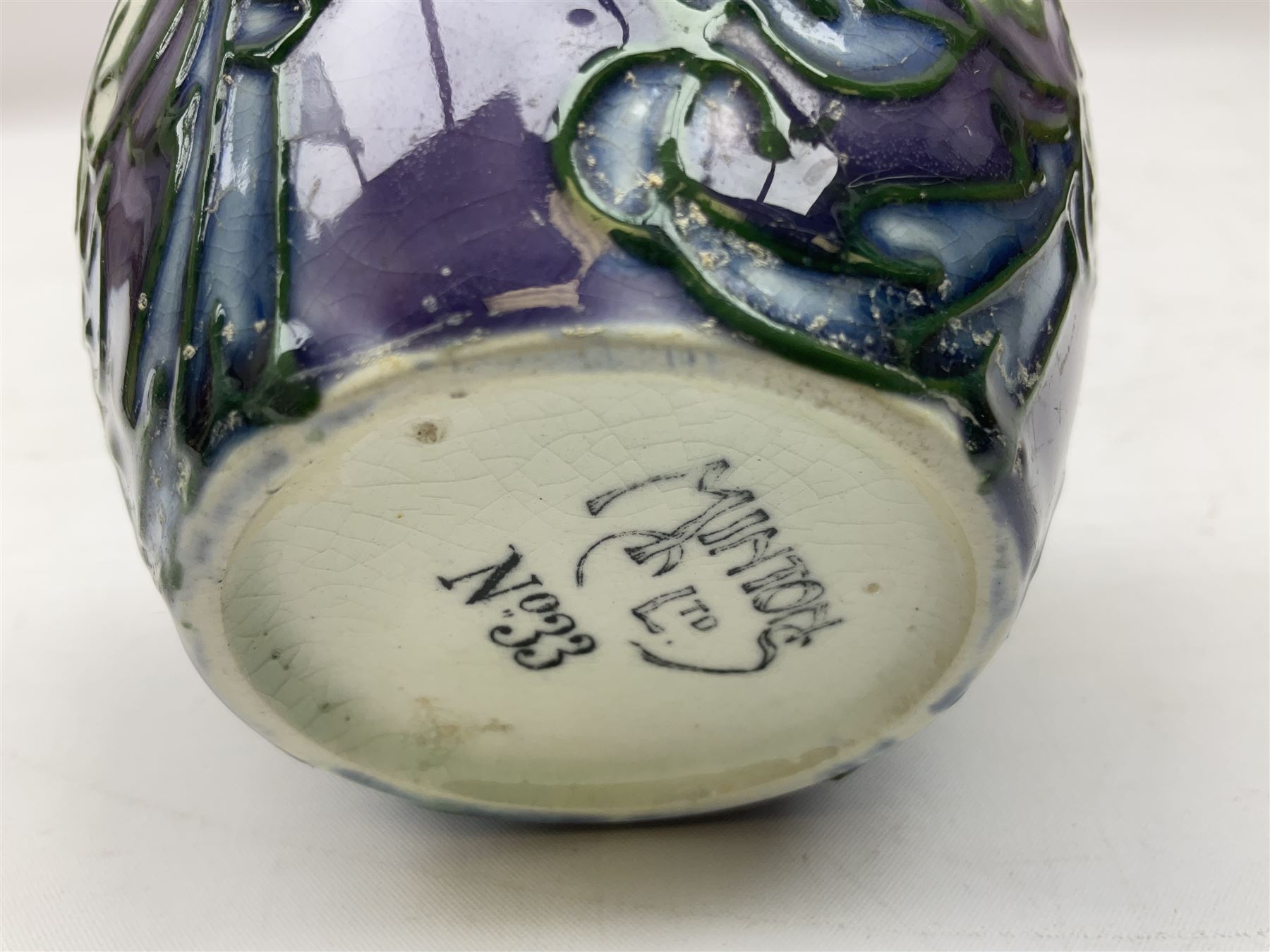 Three Minton Secessionist vases, with tube-lined stylised flower decoration, two upon a red ground and third upon a purple ground, all with printed mark to base 'Minton Ltd, No. 33', H13cm