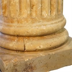 A pair of early 20th century Italian Neoclassical pedestal columns of simplified Doric type; each of fluted cylindrical form in composite stone, finished to evoke weathered limestone or travertine, raised on square plinth bases