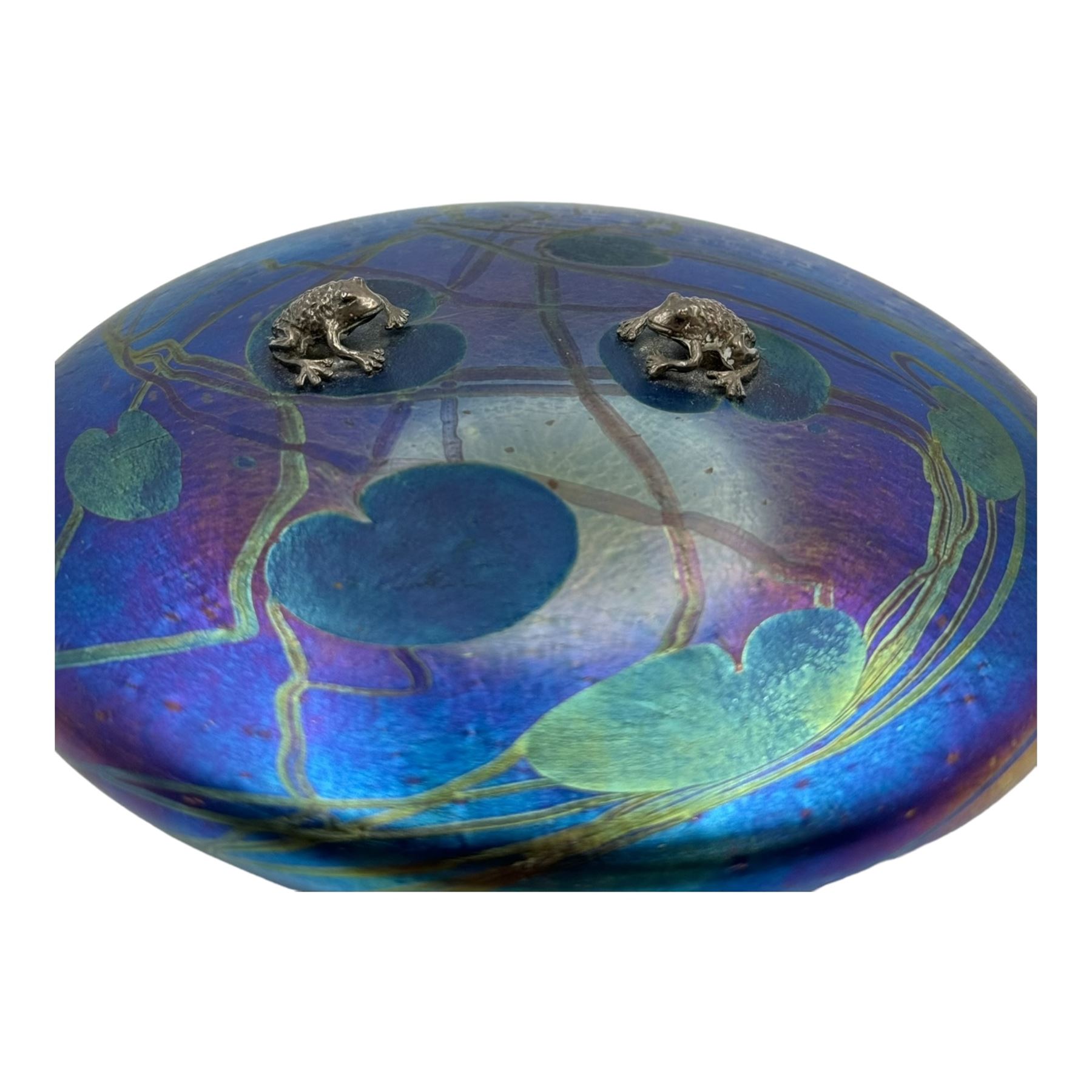 John Ditchfield for Glasform disc paperweight in iridescent purple with green lily trail and a pair of silver hallmarked frogs to top, D14cm