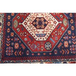 Four small Persian and Caucasian design rugs, comprising a Kazak rug with twin hooked medallions on a red ground, Baluchi rug with geometric motifs on a muted red ground, Shiraz rug with a central ivory and red medallion on a blue ground, and a Bokhara mat with four guls on a rose ground, each enclosed by geometric borders, largest 143cm x 88cm (4)