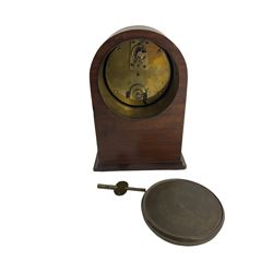 Small Edwardian bedside table clock with a French eight-day timepiece movement and cylinder platform escapement, in a round toped mahogany case with stringing to the sides and raised on bun feet, white enamel dial with Arabic numerals and steel spade hands, convex glass with a cast brass bezel, wound and set from the rear.  With Key.