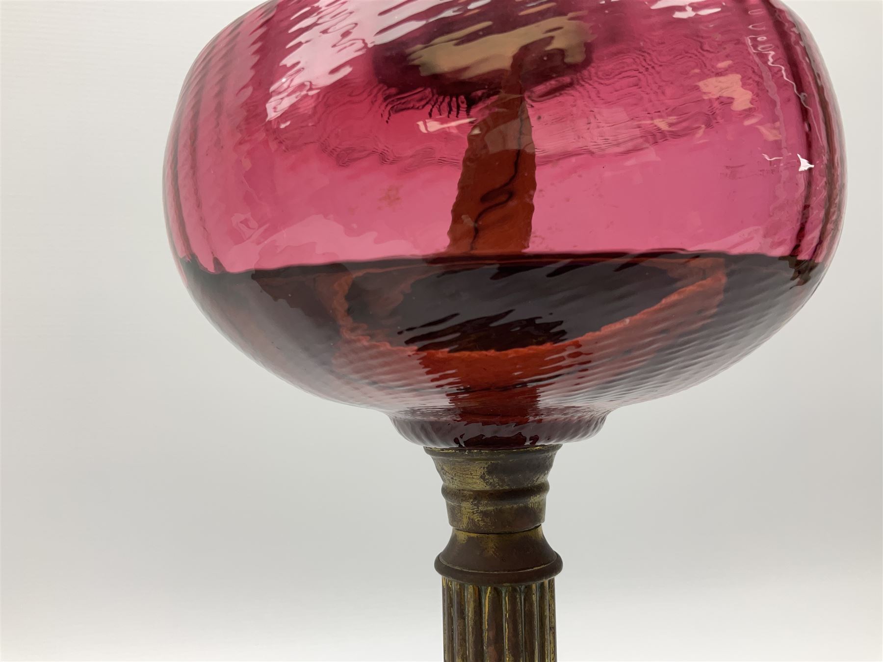 Victorian table standing oil lamp, brass fittings, cranberry glass reservoir, brass column on black enamelled ceramic base, with a frosted glass shade and clear glass chimney, H68cm
